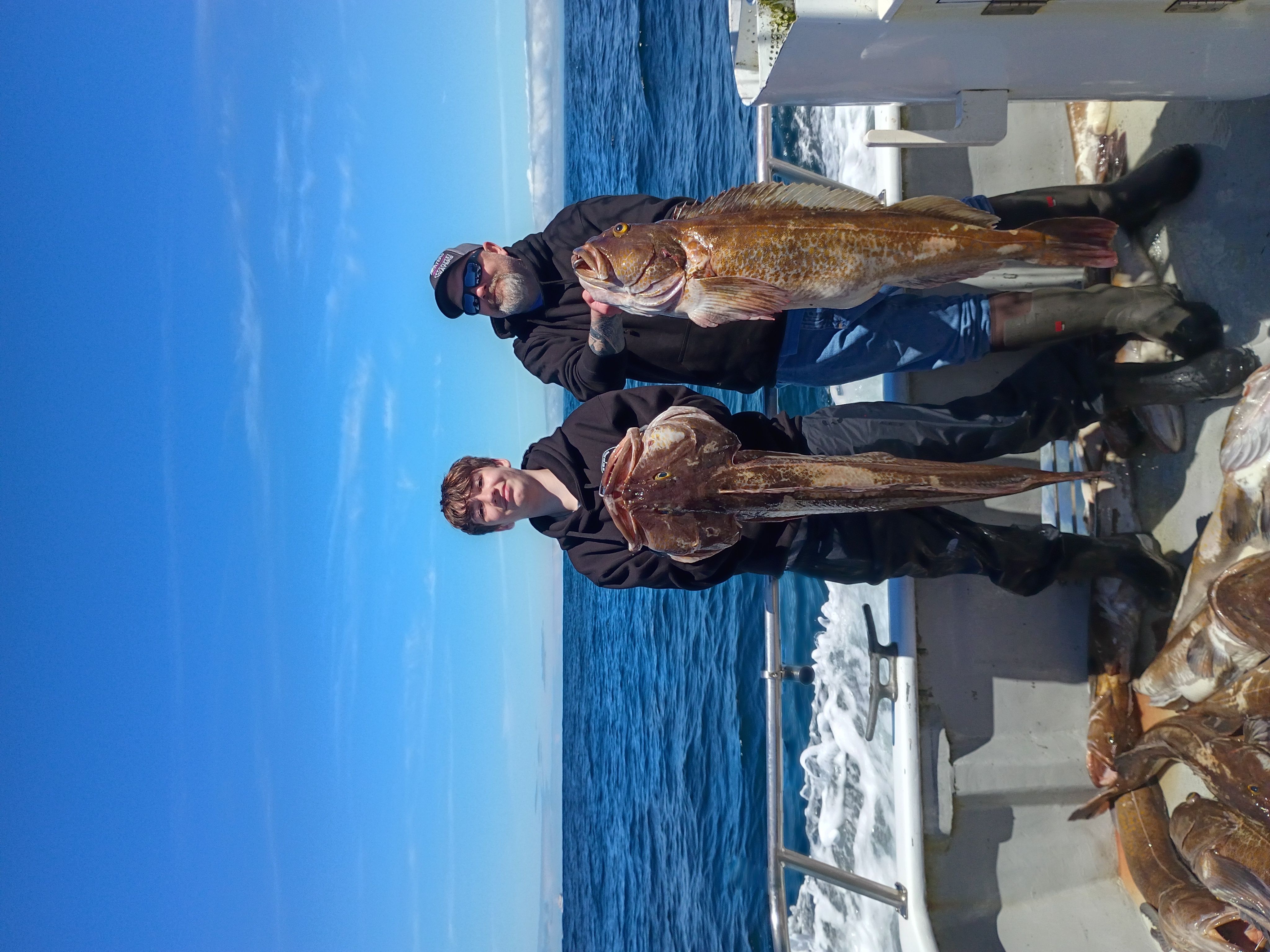 Two anglers with a lingcod aboard the Slammer