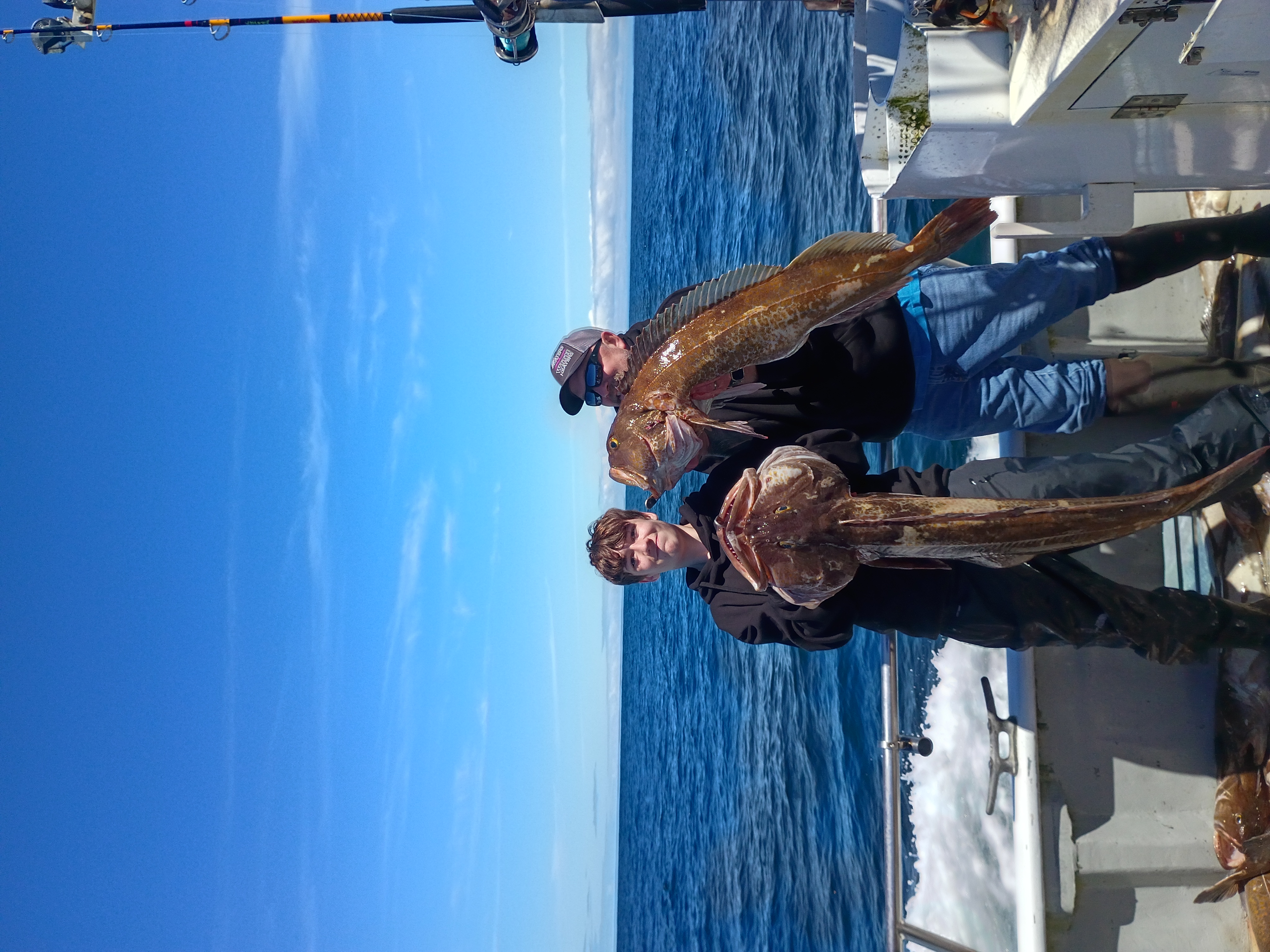 Young angler hauling two big lingcod on deck