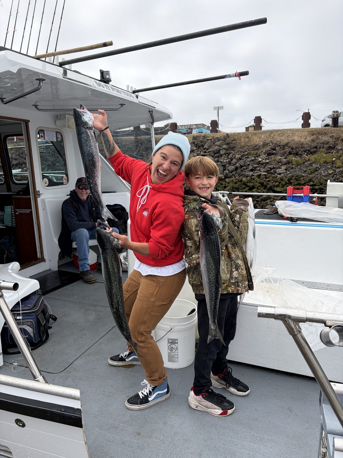 Janna Bronemann holding salmon aboard the Hot Pursuit with a young angler beside her