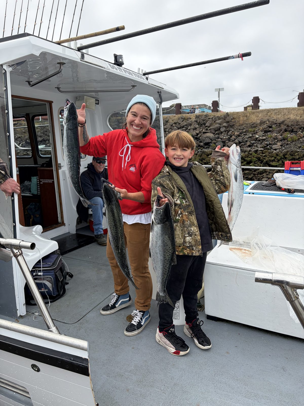 Janna Bronemann and a young angler on the deck of the Hot Pursuit with their salmon