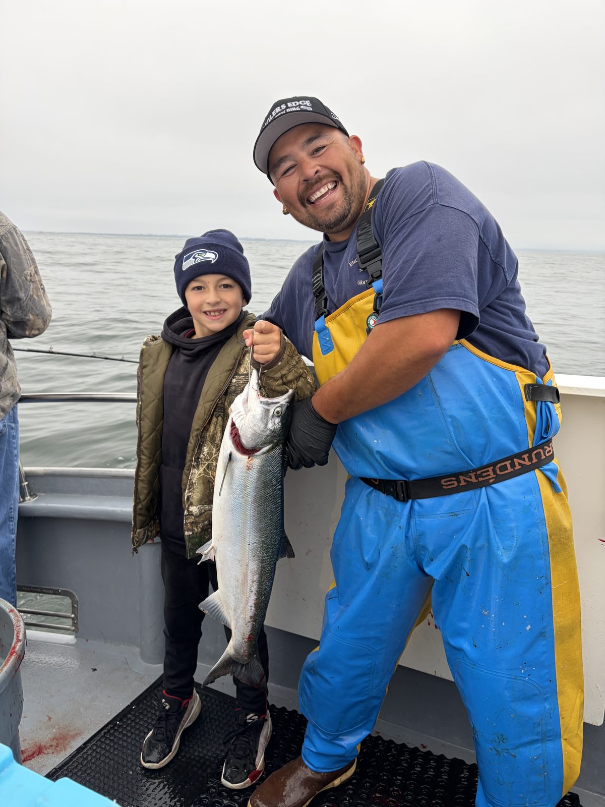 A Hot Pursuit deckhand holding up a salmon next to the young angler who caught it